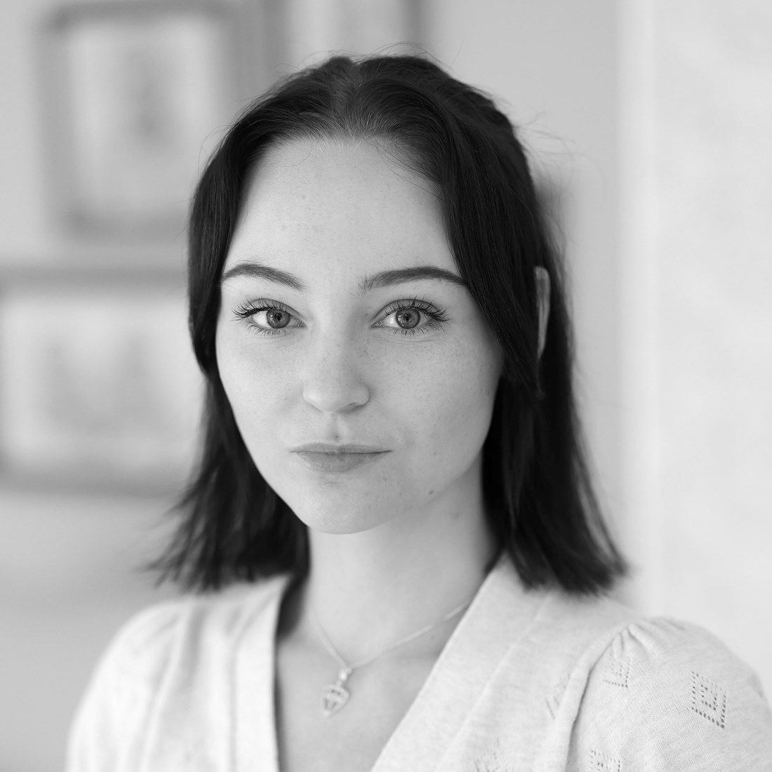 Profilbild på en mörkhårig kvinna med silvrigt halsband och en ljus top